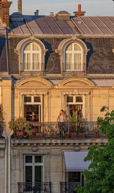 two people are standing on the balcony of an apartment building with plants growing out of their balconies