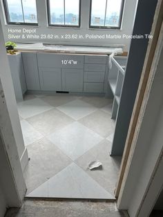 an open door leading to a kitchen with white cabinets and marble flooring in it