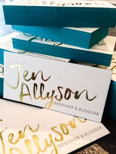 some business cards are stacked on top of each other with gold foil lettering in the middle