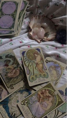 some cards are laying on a bed next to a seashell