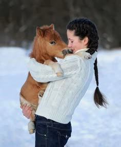 a woman holding a small horse in the snow