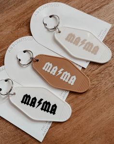 two key chains with the word mama on them sitting on top of a wooden table