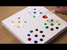 someone is pouring colored liquid on a piece of paper that has been cut into smaller pieces