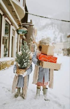 two children carrying presents in the snow on their back legs, one holding a christmas tree