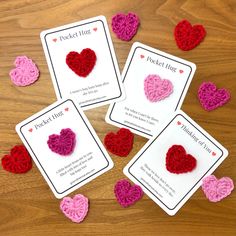 four crocheted hearts sitting on top of a wooden table