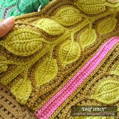 someone is crocheting the leaves on this afghan with yarns and needles in green, pink, yellow and brown colors