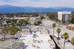 an aerial view of a city street with palm trees and mountains in the back ground