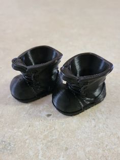 two black baby shoes sitting on top of a floor