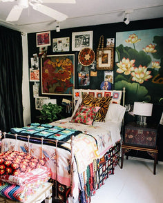 a bed room with a neatly made bed and lots of pictures on the wall above it