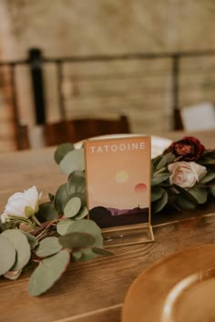 a wooden table topped with flowers and greenery next to a sign that says tattoone