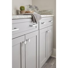 a kitchen with white cabinets and gray counter tops is pictured in this image, there are some utensils on top of the cabinet doors