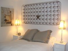 a bed with two lamps on either side of it and a metal headboard above it