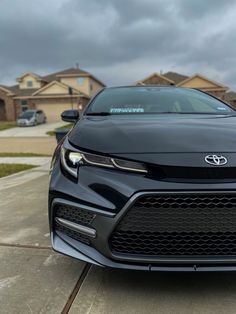 the front end of a black car parked on top of a driveway