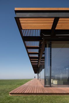 the outside of a house with wooden decking and glass doors on it's side