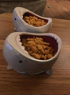 two bowls filled with food sitting on top of a wooden table next to each other