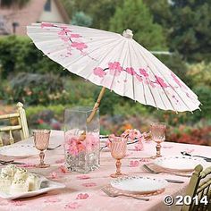 the table is set with pink flowers and an umbrella