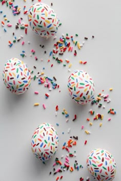 colorful sprinkles and confetti are scattered around three decorated easter eggs