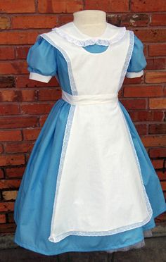 a blue and white dress on display next to a brick wall