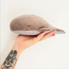 a woman's hand holding up a pillow with a bird on the back of it