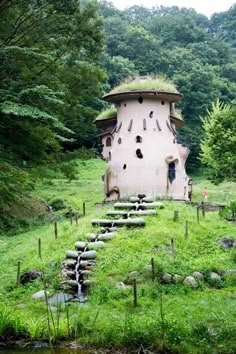 an unusual house in the middle of a green field with steps leading up to it