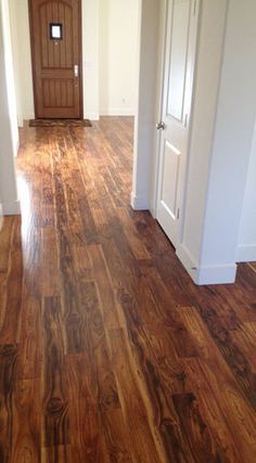 an empty room with hard wood floors and white trim on the door, in front of a wooden door