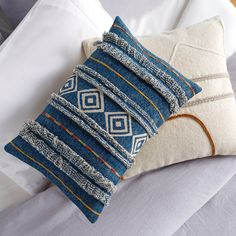 a blue and white pillow sitting on top of a bed