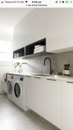 a kitchen with white cabinets and appliances next to a washer and dryer in it