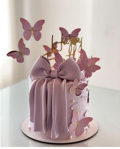 a pink cake decorated with butterflies and ribbons