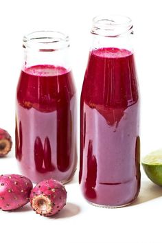 two jars filled with purple liquid next to limes and kiwifruits