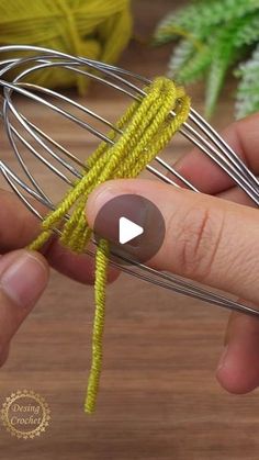 a hand holding a wire whisk on top of a wooden table