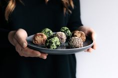 a woman is holding a plate with chocolate and green desserts on it in her hands