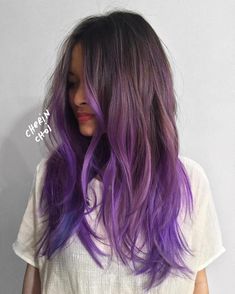 a woman with long, purple hair is standing in front of a white wall and has her hands on her hips