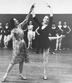 black and white photograph of two women dancing in front of a group of other people