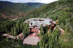 an aerial view of a large home surrounded by trees and mountains in the distance is shown