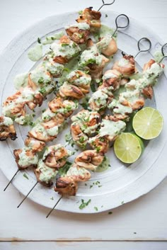 grilled chicken skewers on a white plate with lime wedges