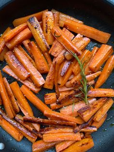 cooked carrots in a frying pan with rosemary sprinkled on top, ready to be eaten