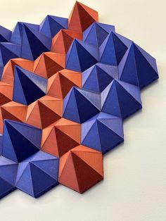 an arrangement of blue, orange and red folded origami pieces on a white surface