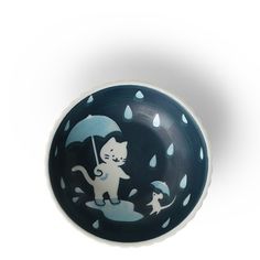 a black and white bowl with a cat holding an umbrella on it's side