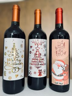 three bottles of wine are sitting on a table with santa claus and snowflakes