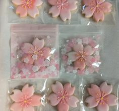 pink and white decorated cookies in plastic wrappers on a tablecloth with flowers inside