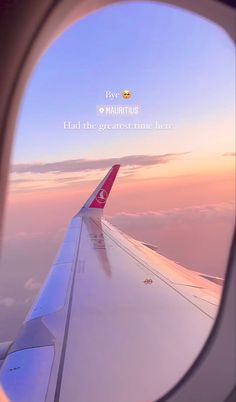 an airplane wing is seen through the window as it flies in the sky at sunset