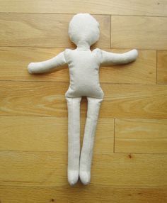 a white stuffed doll laying on top of a wooden floor