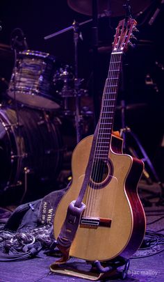 an acoustic guitar sitting on top of a wooden stand