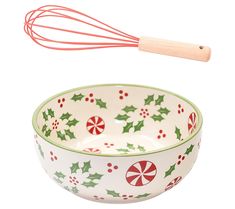 a ceramic bowl with holly and candy canes on it, next to a whisk