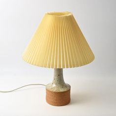 a table lamp with a yellow shade on the top and brown base, sitting on a white surface