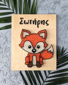 a red fox brooch sitting on top of a piece of wood next to leaves