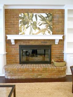 a living room with a brick fireplace and bookshelves on the wall above it