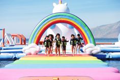 a group of young people standing on top of a rainbow inflatable structure