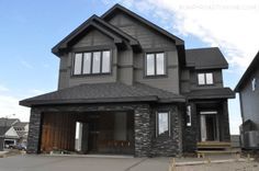 a two story house is shown in the middle of an empty lot with lots of windows