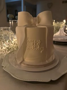 a white birthday cake with a bow on the top and happy birthday written on it